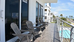 Een balkon met lounge stoelen, een QR-code en een bordje dat een inchecktijd van 2 uur aangeeft.