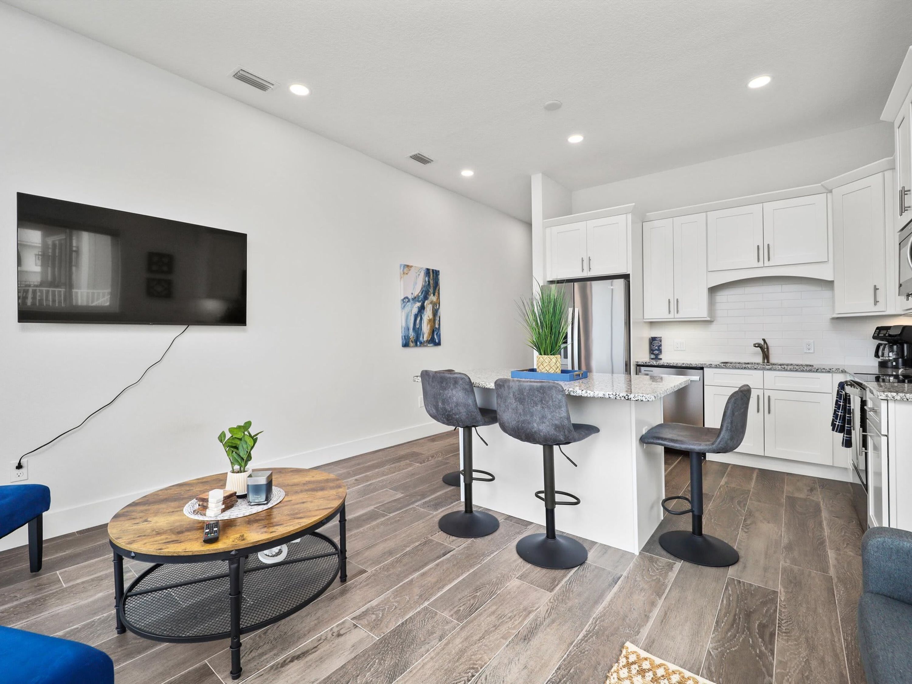 A modern kitchen with white cabinets, a stainless steel refrigerator, and a built-in oven.