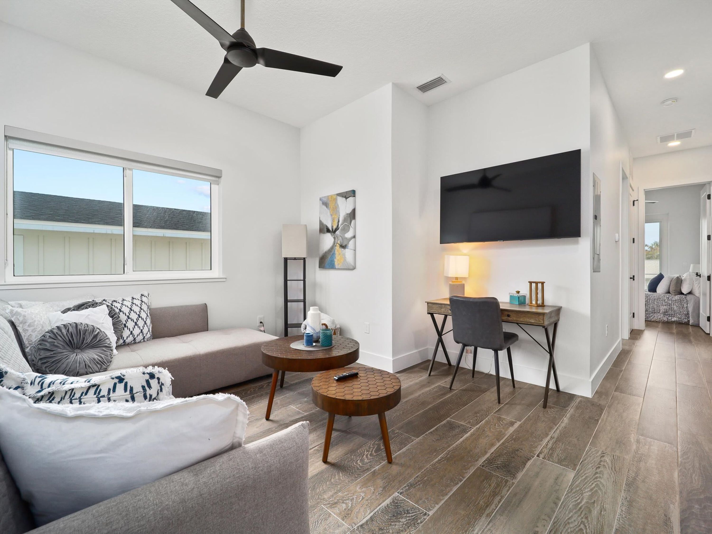 A modern living room with a sofa, coffee table, TV, and a ceiling fan.