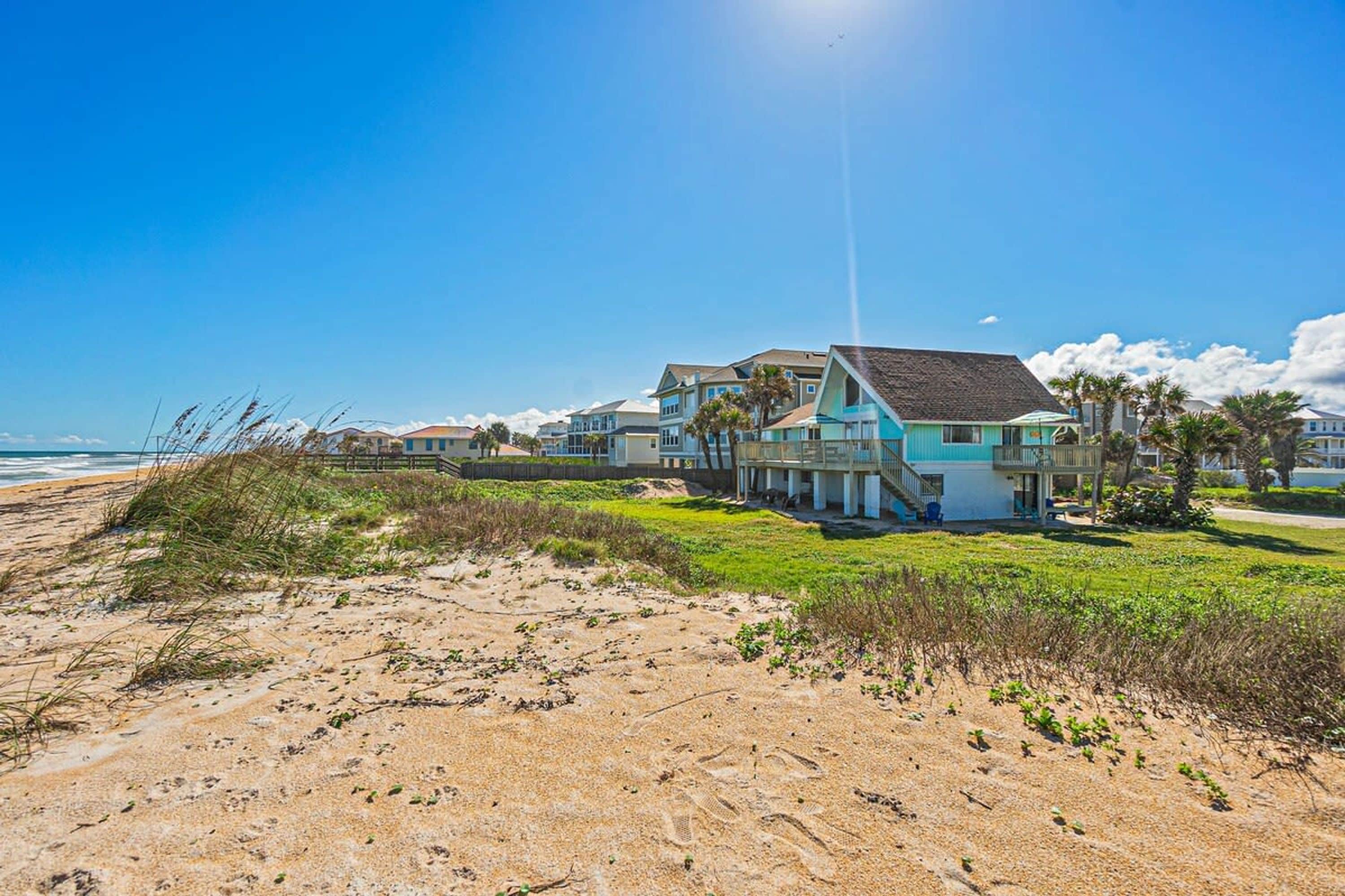 A beachfront property with a large house featuring multiple levels and a prominent balcony.