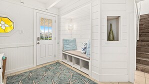 A hallway with a bench, a starfish rug, a door, and a wall-mounted bottle. - Pelican Beach Private Ocean Front Beach House- Sleeps 10 Bring Your Surf Boards (Palm Coast)