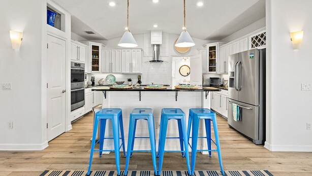 A modern kitchen with white cabinets, a central island with stools, stainless steel appliances, and pendant lighting. - Perfect Beach House 2min Walk With Heated Pool and Hot Tub 4 bed 3 Bath With Pet Friendly (Palm Coast)