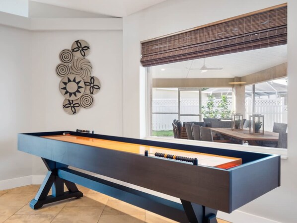 A pool table in a room with a large window overlooking a patio area.