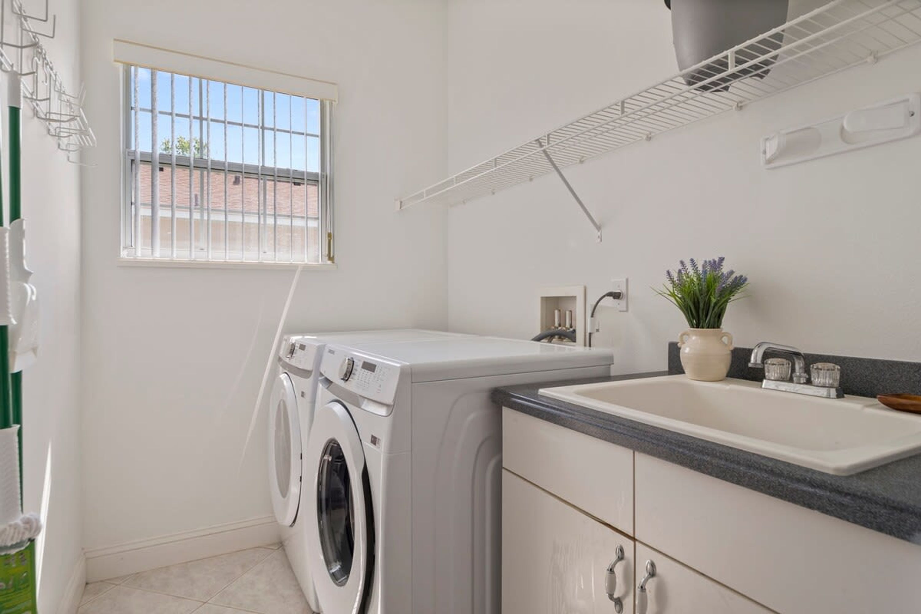 A laundry room with a washing machine, a sink, and a window.
