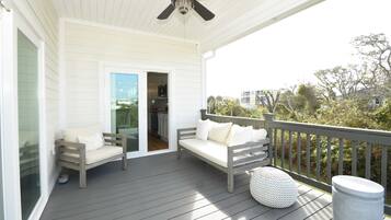 A covered porch with two wooden benches and a ceiling fan.