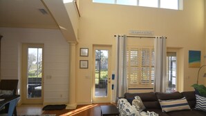 Una sala de estar con sofá, una mesa de centro y un comedor con mesa y sillas. Hay dos puertas que dan a un patio.