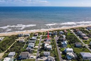 Vista aérea de una zona residencial costera con casas, una playa y el océano.