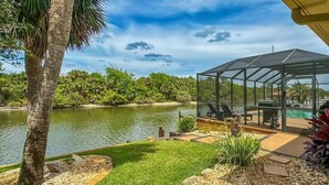 A glass-enclosed outdoor area with a pool, surrounded by greenery and a clear sky.