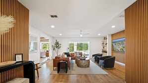 A spacious living area with wooden paneling, a large TV, and a seating arrangement including a sofa and chairs.