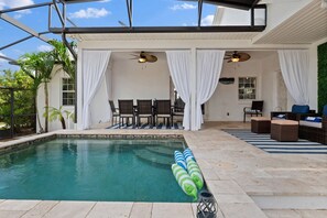 Un espace piscine offrant une vue dégagée sur la piscine, des chaises et un coin salon avec vue sur la verdure environnante.