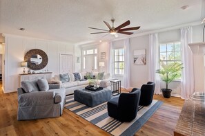 Un salon spacieux doté d’un grand ventilateur de plafond, d’une cheminée et d’une plante en pot.