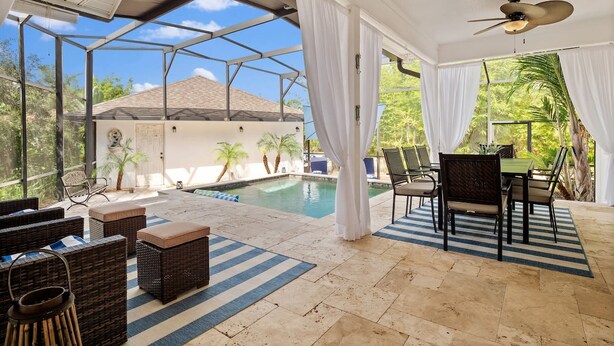 Un espace extérieur abrité comprenant une piscine, des meubles en osier et une table avec des chaises.