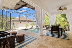 Un espace extérieur abrité comprenant une piscine, des meubles en osier et une table avec des chaises.