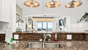 A kitchen with granite countertops, stainless steel sinks, and pendant lighting. - New Luxury Ocean Front 3 Bedroom 2 Bath Condo Sleeps 8 Cinnamon Beach Resort (Palm Coast)