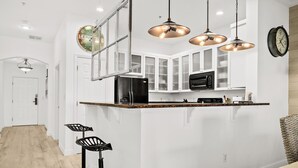 A modern kitchen with white cabinets, a black refrigerator, and pendant lighting. - New Luxury Ocean Front 3 Bedroom 2 Bath Condo Sleeps 8 Cinnamon Beach Resort (Palm Coast)