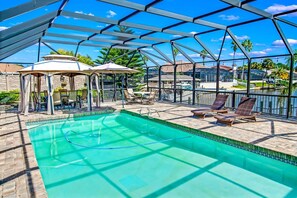 Zona de piscina amb terrassa coberta, gandules i ombrel·les.