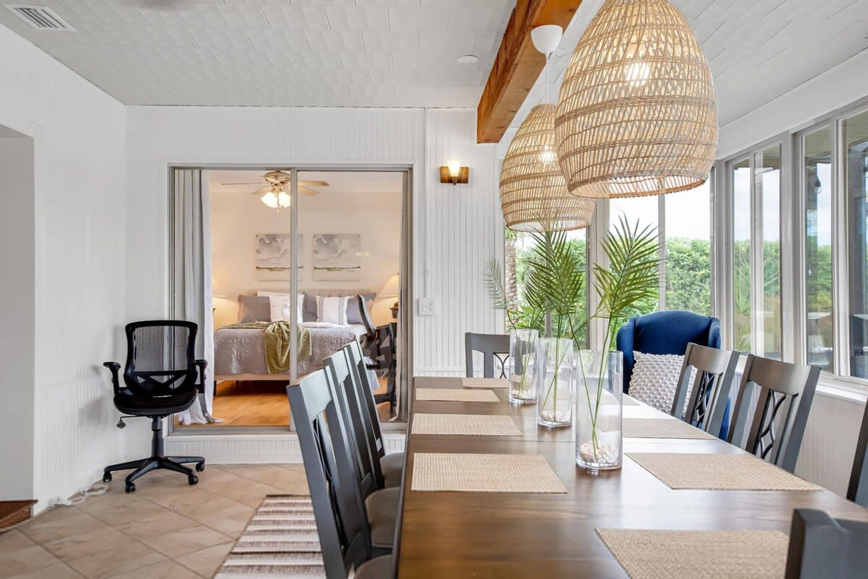 Un espace repas moderne avec une longue table, des chaises et un grand luminaire en fibres tressées.