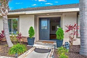 A modern house with a dark front door, potted plants, and a small garden area. - Saltwater Canal Home Heated Pool 3 2 2 Gorgeous Pets Welcome (Palm Coast)