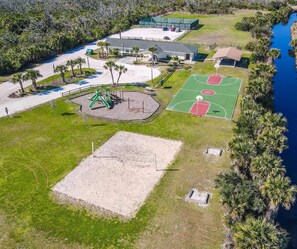 An aerial view of a park with a basketball court, playground, and a building with a green roof. - Saltwater Canal Home Heated Pool 3 2 2 Gorgeous Pets Welcome (Palm Coast)