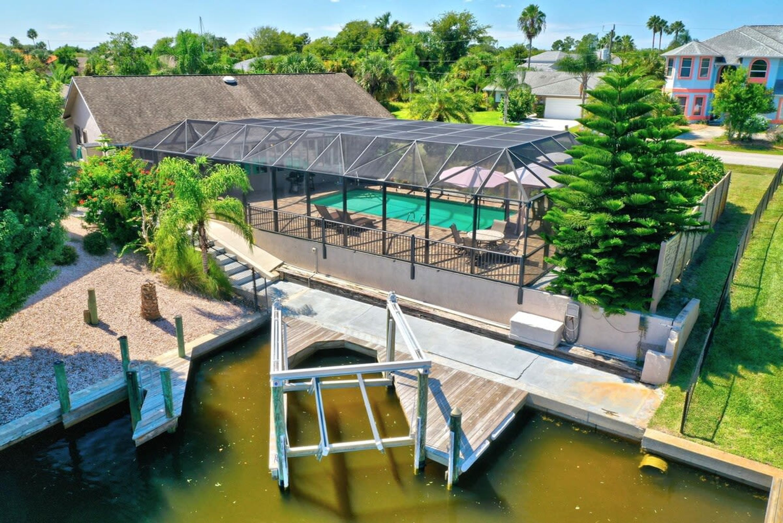 A covered outdoor swimming pool with a glass enclosure, a dock, and a small boat launch area.