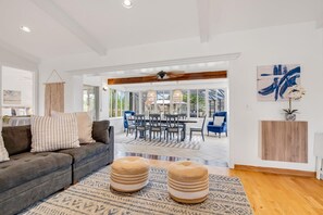 Ein großzügiger Wohnbereich mit Sofa, Poufs und Esstisch.