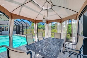 A covered outdoor area with a pool, a table, and chairs. - Saltwater Canal Home Heated Pool 3 2 2 Gorgeous Pets Welcome (Palm Coast)