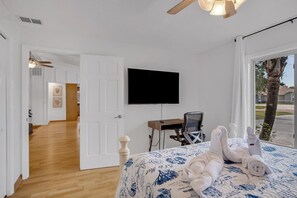 A hotel room with a bed, a desk, a chair, a television, and a view of the outside. - Saltwater Canal Home Heated Pool 3 2 2 Gorgeous Pets Welcome (Palm Coast)