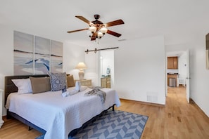 A bedroom with a bed, a ceiling fan, a nightstand, a lamp, and a painting on the wall. - Saltwater Canal Home Heated Pool 3 2 2 Gorgeous Pets Welcome (Palm Coast)