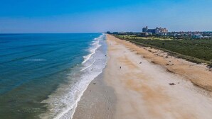 Una playa costera con vista despejada al océano y una hilera de edificios a lo largo de la orilla.