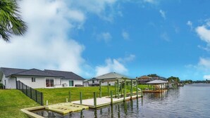 Zona residencial frente al agua con casas, un muelle y un área con césped.