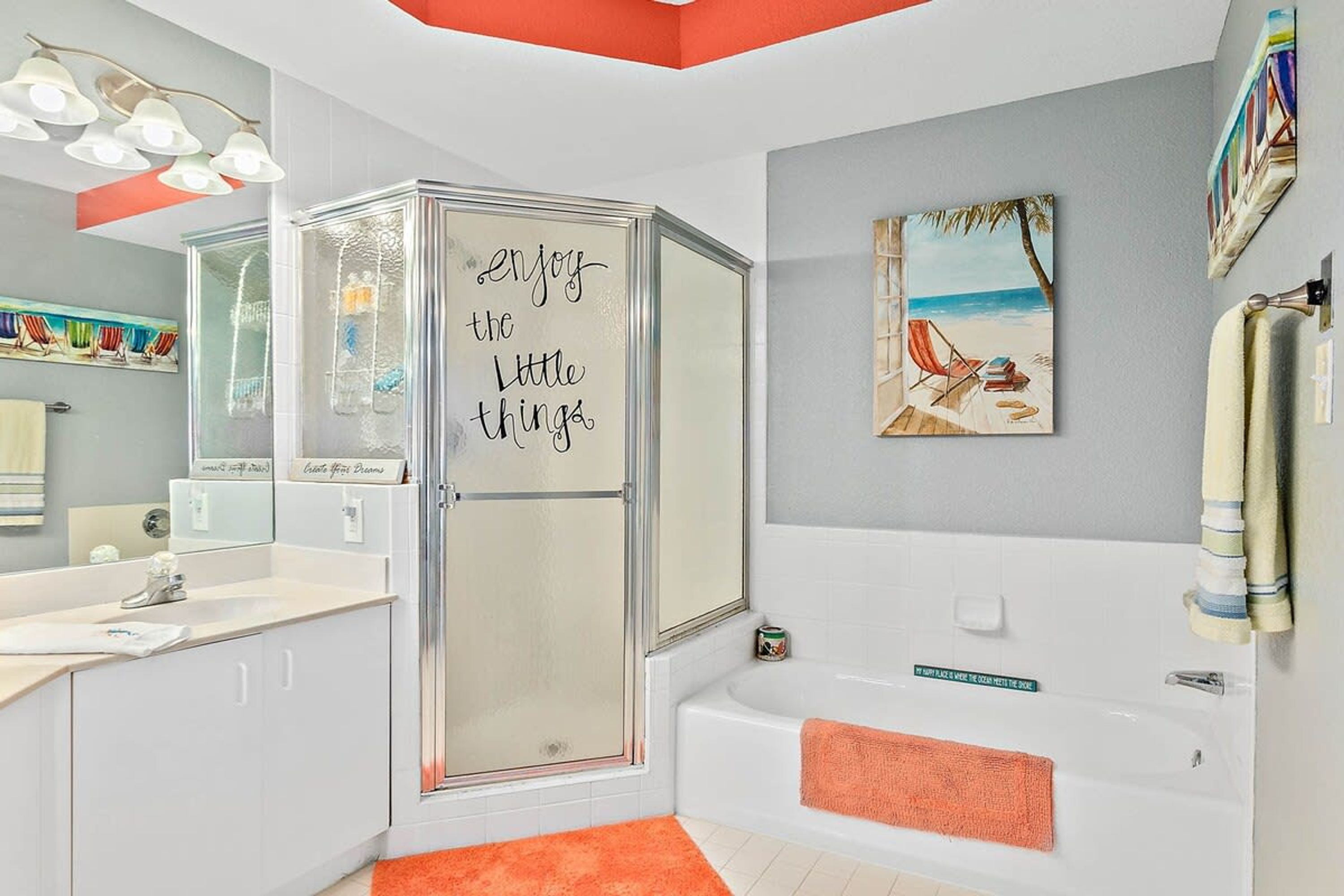 A modern bathroom with a glass shower enclosure, a bathtub, a vanity with a sink, and a towel rack.