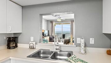 A modern kitchen with a double sink, a coffee maker, and a view of the balcony.
