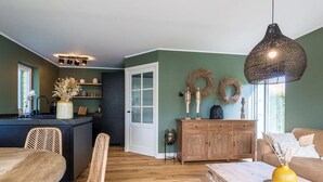 Een moderne keuken met een eethoek, houten meubels en decoratieve kransen aan de muur.