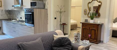 Una sala moderna con un sofá gris, un mueble de madera y un comedor con mesa y sillas.