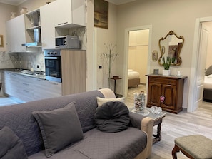 A modern living room with a grey sofa, a wooden cabinet, and a dining area with a table and chairs.