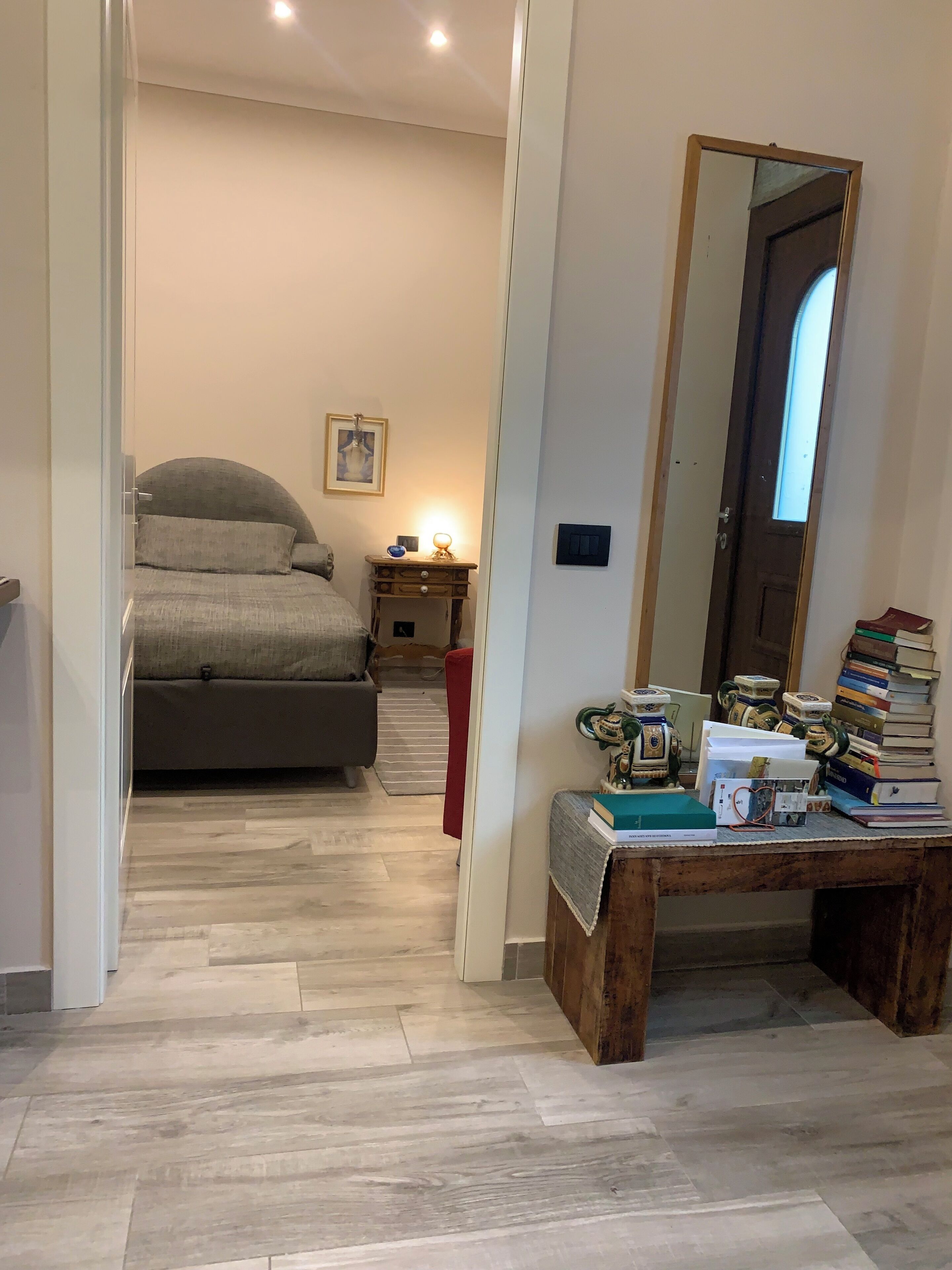 A bedroom with a bed, bedside table, and a mirror.