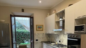 A modern kitchen with a dining area, featuring a large window, a refrigerator, a stove, and a microwave. - LUCCA MIRA (Lucca)