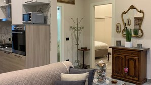 A living room with a beige sofa, a wooden cabinet with a mirror, and a dining area with a white table and chairs. - LUCCA MIRA (Lucca)