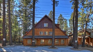 A log cabin hotel with a central entrance, multiple windows, and a surrounding forest. - Big 10 Luxury Cabin with HotTub (Big Bear Lake)