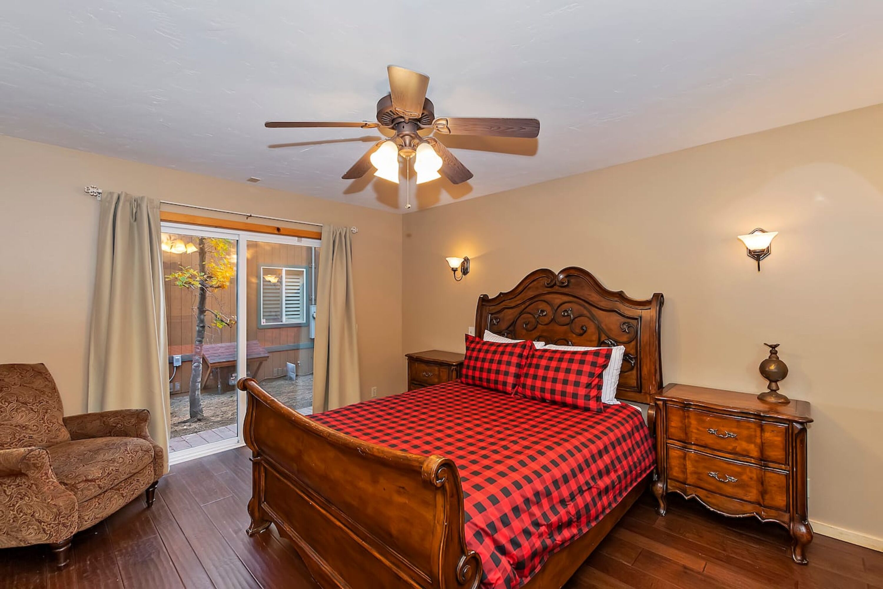 A bedroom with a wooden bed, a ceiling fan, a nightstand, and a chair.
