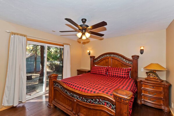 A bedroom with a wooden bed, a ceiling fan, a nightstand, and a lamp.