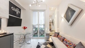 Una sala de estar moderna con un sofá, una mesa de comedor de vidrio y una zona de cocina.