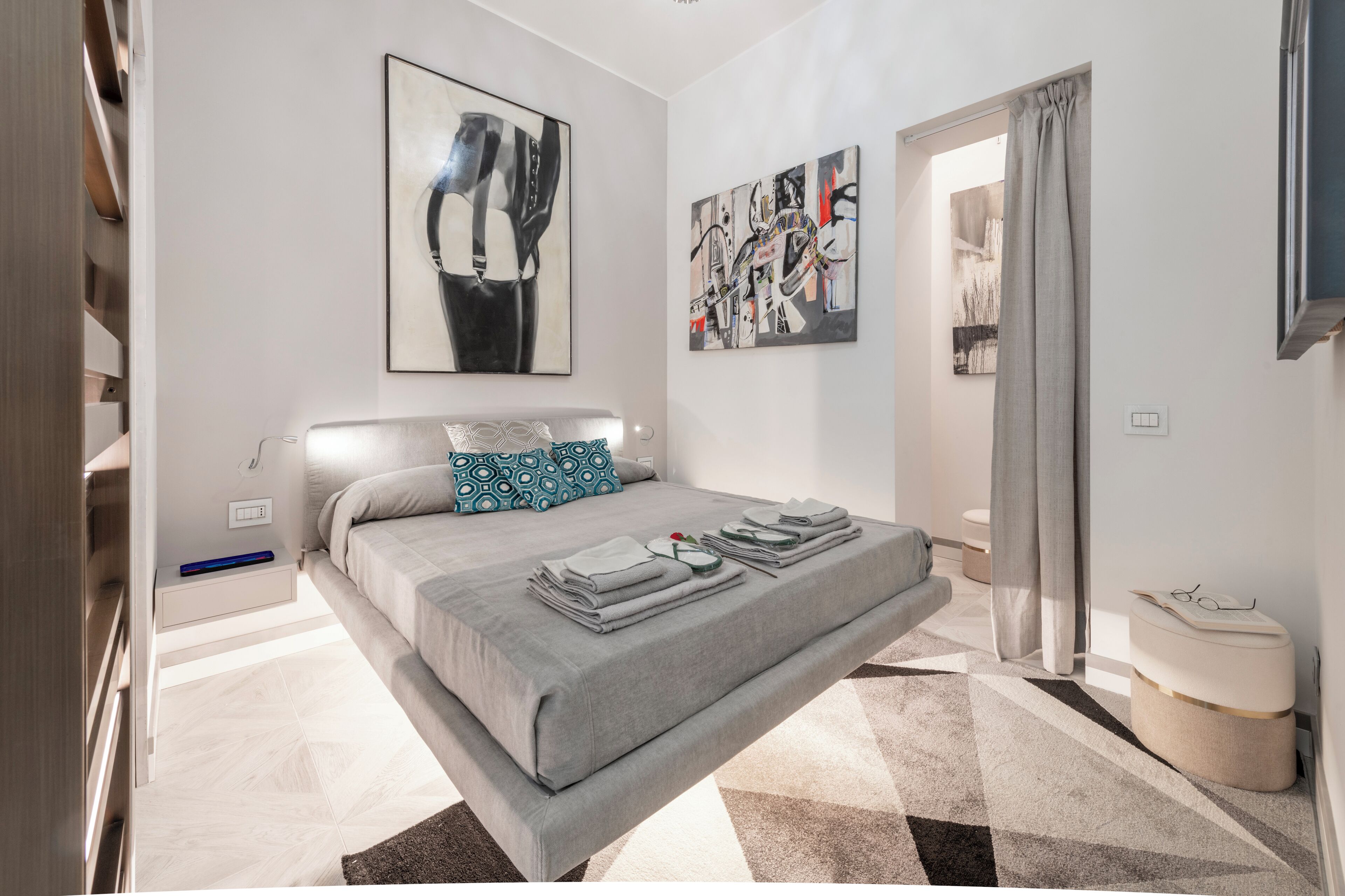 Ein modernes Schlafzimmer mit Bett, Kunstwerken und Blick auf einen Flur.