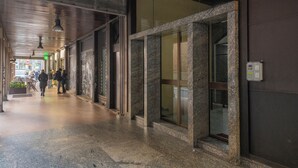 Un pasillo con pared de piedra, puerta de cristal y un cartel con un número que indica la ubicación.