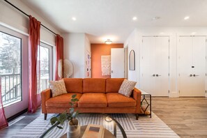 Un salon moderne avec un canapé, une table basse et une vue sur l’extérieur.