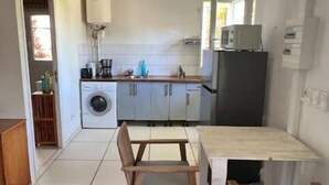 A compact kitchen with a dining table and chairs, a washing machine, and a refrigerator. - TI KAZ with SPA and nearby lagoon (Saint-Paul)