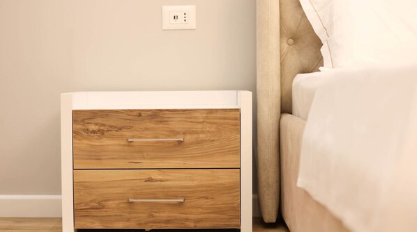 A bedroom with a wooden nightstand, a bed, and a wall socket. - Grandstay Apartments 007 (Durrës)