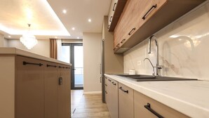 Een moderne keuken met houten kastjes, een marmeren aanrecht en een roestvrijstalen kraan.