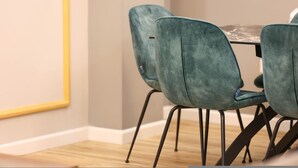 Een eetgedeelte met een tafel en vier teal-kleurige stoelen met metalen poten.