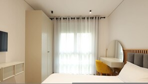 Une chambre à coucher moderne, avec un lit, un bureau, une chaise, un miroir et un téléviseur.